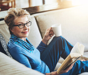 Happy, senior woman and glasses with book or story on sofa funny literature in retirement home....