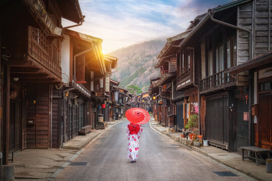 Asian woman wearing a traditional Japanese kimono holds an umbrella at Narai Juku in Nagano, Japan. Translation Narai Juku Village.. - Powered by Adobe