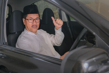 A man sitting in a driver's seat while raising his thumb