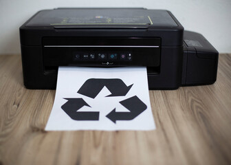 Paper with an icon about recycling coming out of a printer