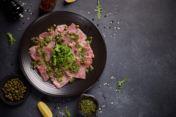 tuna carpaccio - slices of fresh raw tuna fillet on black ceramic plate