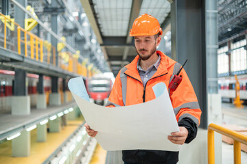 Engineer Reviewing Blueprints in Train Workshop
