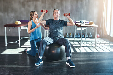 Fitness, personal trainer and senior man with dumbbell in gym for physiotherapy, support or...