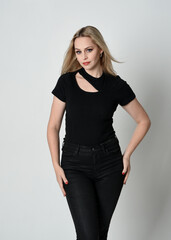 Close up portrait of beautiful blonde woman wearing modern black shirt and leather pants. Confident  standing pose with hand gestures, isolated on white studio background.