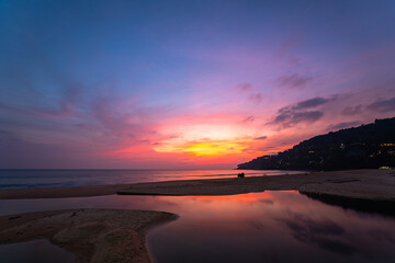 Fototapeta premium sweet sky at sunset reflection in the beach puddle. The sun's rays glistened in the puddle creating a mesmerizing dance of colors. stunning colorful reflection in sea surface.colorful sky