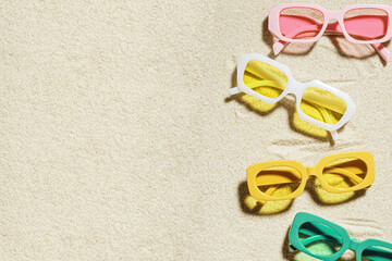 Stylish colored sunglasses on sand background at sunlight, summer fashion eyeglasses with colors glass. Summer sale concept in optical store. Top view lifestyle aesthetic photo, copy space