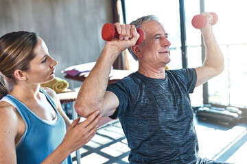 Elderly man, physiotherapist and exercise with dumbbell in clinic for rehabilitation, support or...