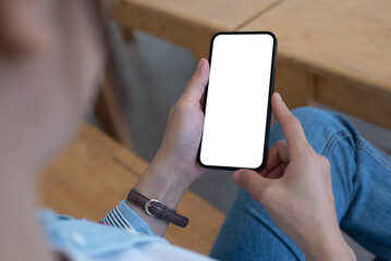 Mockup, woman's hands holding mobile phone with blank screen in coffee shop, over shoulder view