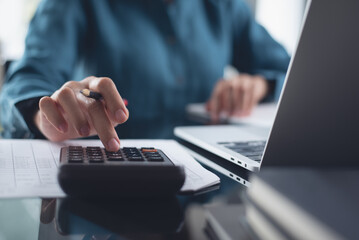 Close up of businesswoman or accountant working on calculator to calculate business data,...