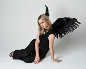 Full length portrait beautiful blonde girl wearing modern black shirt, leather pants, feather angel...