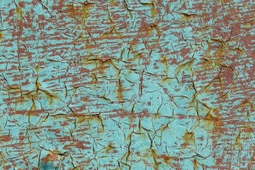 Old dried paint with cracks on a rusty metal surface. Textured rough surface with cracked paint. Corrosion of the metal and the sun cause cracking of the painted surface.