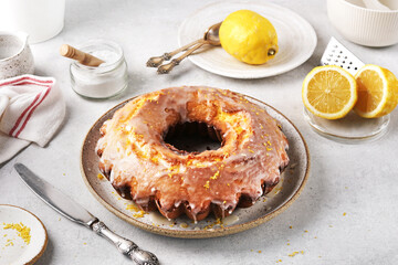 Lemon bundt cake drizzled with powdered sugar glaze on a light table