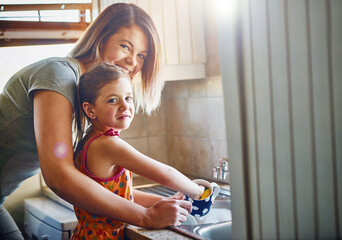 Portrait, mother and child washing dishes in home for hygiene, housework and learning. Face, mom and kid cleaning cup for chores, housekeeping or happy parent teaching girl for help in family kitchen - Powered by Adobe