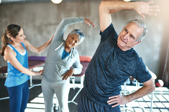 Stretching, support and senior people in physical therapy for help with muscle fitness and wellness by physiotherapist. Exercise, workout and recovery in hip and spine of mature clients in class