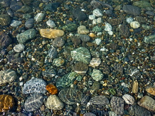 Colorful Sea Pebble stones and rocks underwater on beach. Different forms multicolor Pebbles (green, orange, grey, black) as natural abstract texture background. Close up colorful Pebbles on coast.