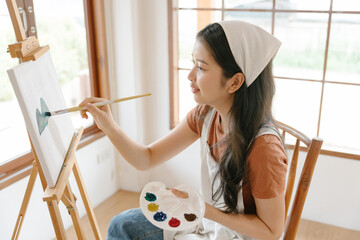 Asian young talented woman artist coloring on painting board in house. Attractive beautiful female...