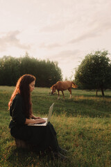 Woman using laptop in IT outside in eco-farm. Online chat. Spend free time on nature. Concept...