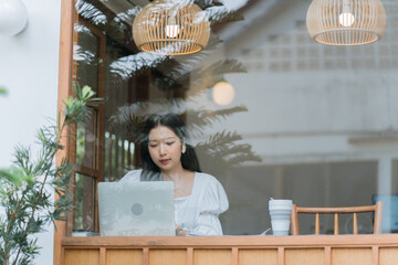 Beautiful young woman working with computer at cafe drinking coffee and typing on a keyboard.