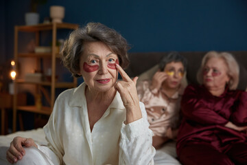 Portrait of beautiful elderly woman with eye patches sitting on bed