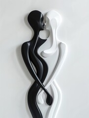 A black and white sculpture of two figures, one dark and one light, embracing. The figures are stylized and have smooth, flowing lines. The sculpture is mounted on a white base.