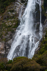 waterfall close up with water details dropping on rocks surrounded by green trees