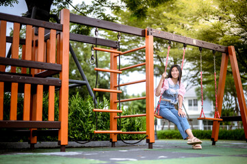 A young woman sits alone on a swing at the village park.