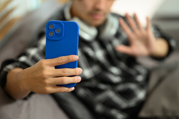 Close up view of male hands using smartphone taking selfie while sitting on couch at home