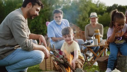 A father and little boy son happily start a campfire during a family camping trip in nature - Powered by Adobe