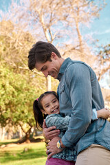Fototapeta premium Girl, portrait and happy in hug with dad in park on school, holiday or vacation on weekend for growth. Family, bonding and childhood development in nature with smile for memory, together and support