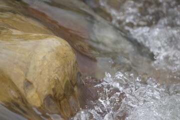 Smooth rock with water pouring over it, rough waters