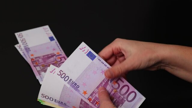 Close-up female hands counts different euro money banknotes. Puts money in different stacks at face value.