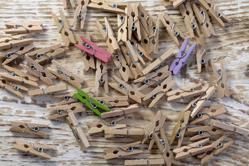 Set of decorative clothespins with bright red one on white wood background