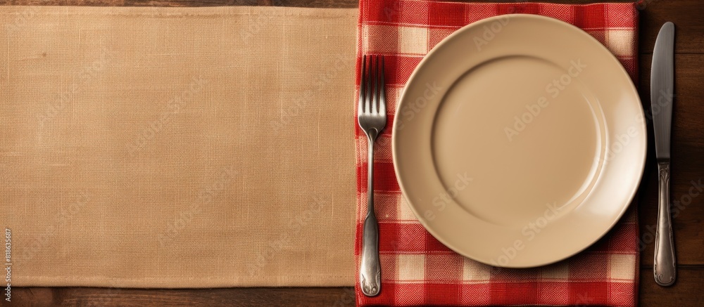 Fototapete A top view of a table setting with an empty plate a knife a fork and a napkin providing ample copy space for customization