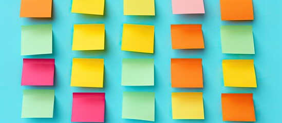 Colorful sticky notes arranged on a turquoise background with a flat lay layout There is ample space to add text or captions to the image