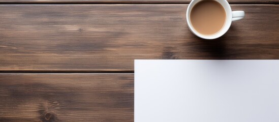 On a wooden table there is a cup of coffee and a notepad with ample copy space image