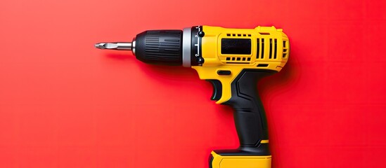 The image shows a red drill placed on a yellow background in a flat lay style leaving enough empty space for additional content