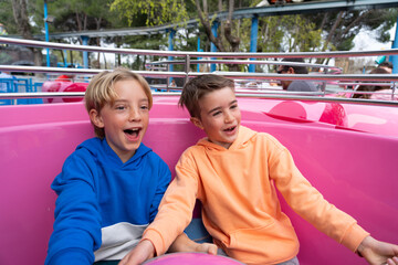 Two Caucasian children having fun on a cup ride at an amusement park