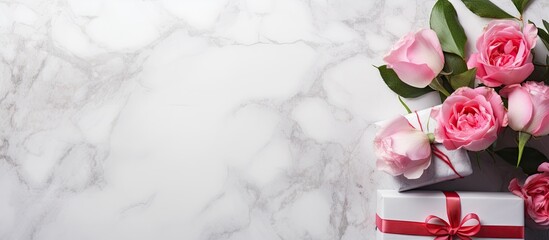 A white marble background with pink roses gift boxes and a spring holiday theme offers a copy space image