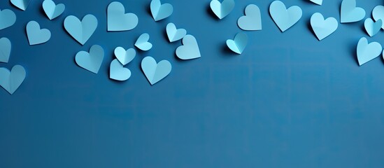 Flat lay style with a blue paper background showcasing numerous hearts in a copy space image