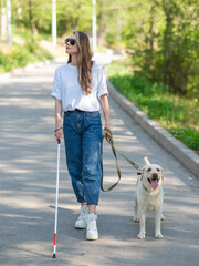 Blind woman walking with guide dog in the park. 