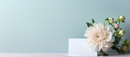 A fresh flower decoration creates an attractive backdrop for a blank white paper note standing upright on the table Copy space image