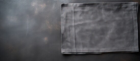 Top view of a linen kitchen towel napkin placed on an aged black ceramic cement table providing a...