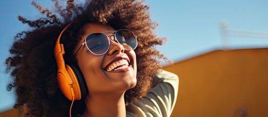 A cheerful young black hipster girl with stylish glasses enjoys her free time outdoors creating a...