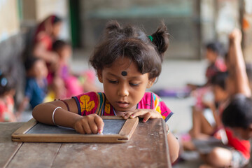 Anganwadi School girl writing on slate at school in west bengal