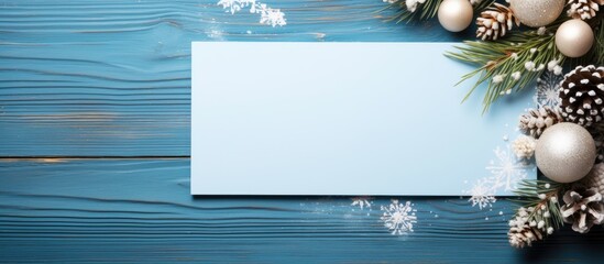 A festive composition on a blue wooden table featuring a blank greeting card Christmas decorations and plenty of space for adding text. with copy space image. Place for adding text or design - Powered by Adobe