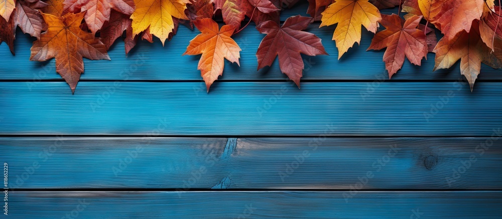Poster autumn leaves in vibrant colors beautifully contrast against a backdrop of blue and brown wooden sur
