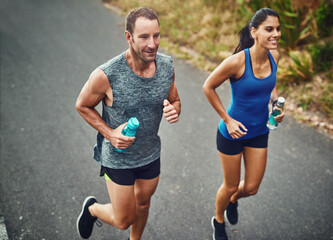 Fitness, running and couple with smile, marathon and bottle for hydration with water and outdoor....