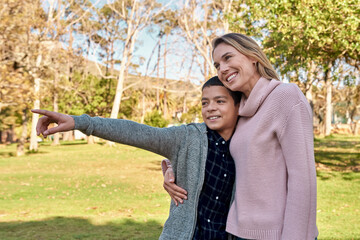 Child, pointing and outdoor at park with mom on holiday, vacation or travel on adventure with hug. Happy, family and mother with kid sightseeing in woods, forest or explore countryside or learning