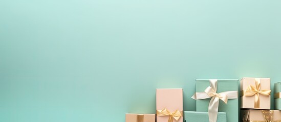A minimal flat lay arrangement with pastel colored gift boxes on a turquoise background featuring...
