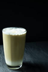 Glass of latte coffee on grey and black background